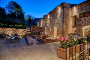 a stone building with a patio with tables and flowers at Relais La Costa Historical Residence in Monteriggioni