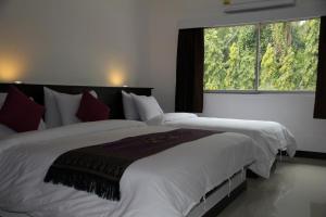 a bedroom with a large bed with a large window at Sri Chumphon Hotel in Chumphon
