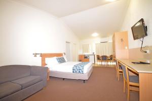 Habitación de hotel con cama y sofá en Boulevarde Motor Inn, en Wagga Wagga