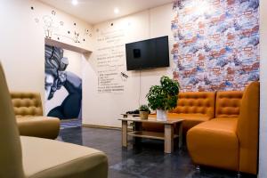 a waiting room with couches and a tv on a wall at Maestro Hostel in Saint Petersburg