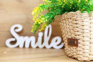 Ein Korbkorb mit dem Wort Lächeln neben einer Pflanze in der Unterkunft Gile Guest House in Weliko Tarnowo