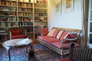 een woonkamer met een bank en stoelen en een boekenplank bij Domaine de la Charmeraie in Saint-Cirq