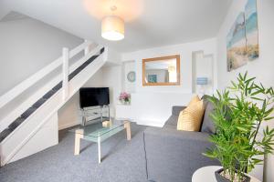 a living room with a couch and a tv and stairs at Stop Looking! Walk to the City Center - TV in every Bedroom! in Swansea