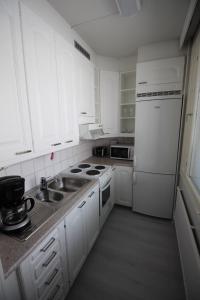 a white kitchen with a sink and a refrigerator at Apartment Kirkkokatu in Raahe