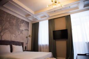 1 dormitorio con 1 cama y TV en la pared en TELEGRAPH INN, en Petropavlovsk