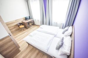 a bedroom with a bed with white sheets and pillows at Hotel Turmfalke in Linz