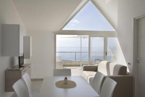 a living room with white furniture and a large window at Airone Residence in Zambrone