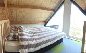 een slaapkamer met een bed in een kamer met ramen bij Huisje op Hamingen in Staphorst