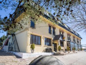 a yellow building with blue windows and potted plants at Hotel El Prado by Vivere Stays in Carrascosa del Campo