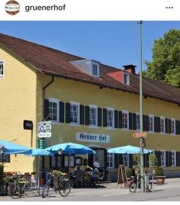 ein Gebäude mit Tischen und Sonnenschirmen davor in der Unterkunft Hotel-Gasthof Grüner Hof in Freising