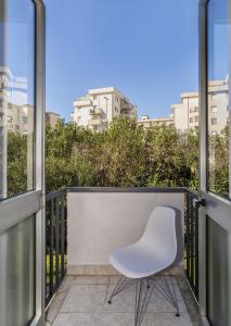una silla blanca sentada en un balcón con ventanas en BB L'APPRODO, en Pisa