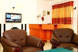 a living room with two chairs and a tv at Hotel Birds View in Tissamaharama