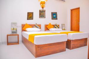 a bedroom with two beds with orange and white pillows at Amuththa Resort in Anuradhapura +37 photos