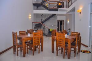 a dining room with wooden tables and chairs and a staircase at Amuththa Resort in Anuradhapura