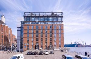 een groot bakstenen gebouw met auto's geparkeerd voor het bij GINN Hotel Hamburg Elbspeicher in Hamburg