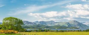 a field with a view of a lake and mountains at Barcaldine Castle in Oban