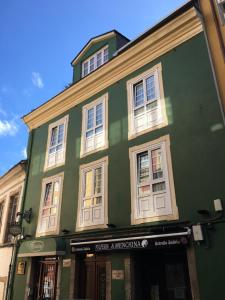 un edificio verde con ventanas blancas en una calle en Escuder Apartamentos Turísticos, en Ribadeo