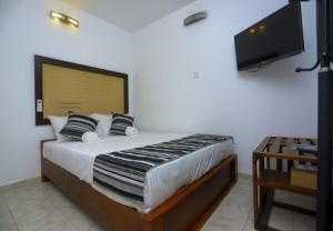 une chambre avec un grand lit et une télévision à écran plat dans l'établissement Vendol Sky Resort, à Kandy