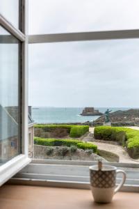 een koffiekopje op een vensterbank met uitzicht op de oceaan bij Le Plongeoir by Cocoonr in Saint-Malo