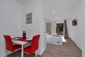 una sala da pranzo bianca con tavolo e sedie rosse di Apartman-Studio Meri a Makarska