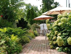 a patio with two umbrellas and chairs on a brick path at Moffat Inn in Niagara on the Lake
