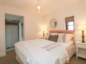 een slaapkamer met een groot wit bed en 2 lampen bij Fosfelle Cottages in Bideford