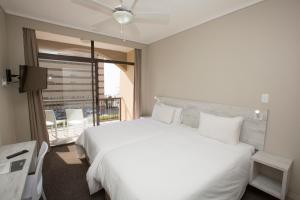 a bedroom with a large white bed and a balcony at 14 on Marine in East London