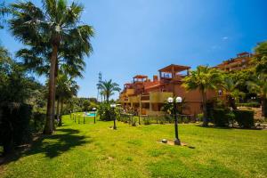 um parque com palmeiras em frente a um edifício em Apartamento la Reserva de Marbella em Marbella
