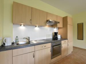 a kitchen with wooden cabinets and a sink at Quaint Apartment in Zierow near Sea in Zierow