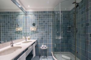 a blue tiled bathroom with two sinks and a shower at UNA HOTELS Capotaormina in Taormina