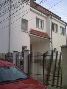 una casa bianca con una recinzione e una macchina rossa di vila Irina a Constanţa