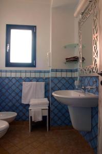 Hotel Nautico Pozzallo في بوزالو: حمام ازرق وابيض مع مغسلة ومرحاض