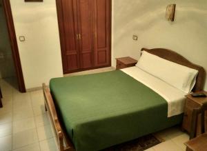 1 dormitorio con cama verde y armario de madera en Hostal Gaudí, en Madrid