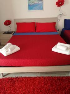 ein Bett mit roter Bettwäsche und weißen Handtüchern darauf in der Unterkunft House of colours in Alghero