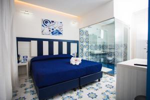 a bedroom with a blue bed and a bathroom at OASI FANTASIA in Agerola