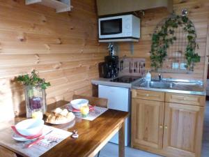 een keuken met een tafel, een wastafel en een magnetron bij laroulottedubec in Malleville-sur-le-Bec