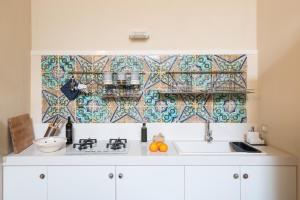a kitchen with a sink and a tile wall at Jasmine Modica Luxury House in Modica