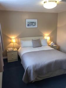 a bedroom with a large bed and two lamps on tables at Newent Golf Club and Lodges in Newent