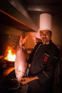 un homme dans une cuisine tenant un grand poisson dans l'établissement Kubura Resort, à Anurâdhapura