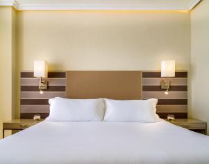 a bedroom with a large bed with two lamps on it at H10 Gran Tinerfe - Adults Only in Adeje