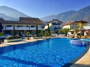 a swimming pool in a resort with mountains in the background at Schlosshof Charme Resort – Hotel & Camping in Lana