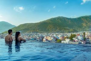 Un uomo e una donna in piedi in una piscina a sfioro con una città di Hotel Sabrina, Kathmandu a Kathmandu