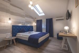 a bedroom with a blue bed and a television at SCHLOSSHOF SÜDTIROL - Hotel & Camping Resort in Lana