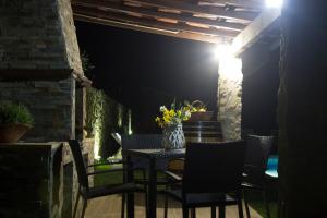 einen Tisch mit Stühlen und eine Vase mit Blumen auf einer Terrasse in der Unterkunft Casa do Ribeiro in Sever do Vouga