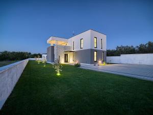 una gran casa blanca con luces en el césped en Villa Lungera, en Štinjan