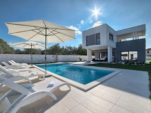 una casa con piscina con sillas y sombrilla en Villa Lungera, en Štinjan