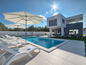 a house with a swimming pool with chairs and an umbrella at Villa Lungera in Štinjan