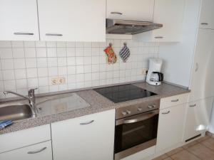 een keuken met witte kasten en een wastafel bij Ferienwohnung Elgert in Scheidegg