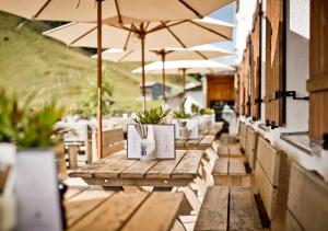 a row of wooden tables with umbrellas on a patio at Berghotel Altes Wallberghaus in Rottach-Egern