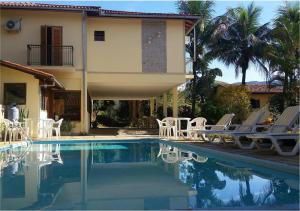 a swimming pool with chairs and a house at Pousada da Figueira in Conservatória